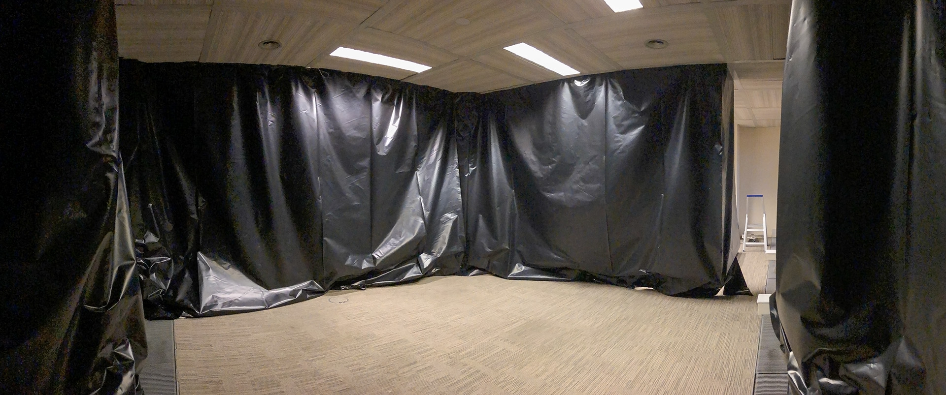 Wide angle view from inside of the camera obscura during construction. The walls of the camera are made of thick, black plastic hanging off the ceiling forming an almost completely closed off area.